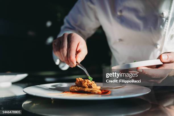 a chef is finishing the preparation of the plate - cuisine 個照片及圖片檔