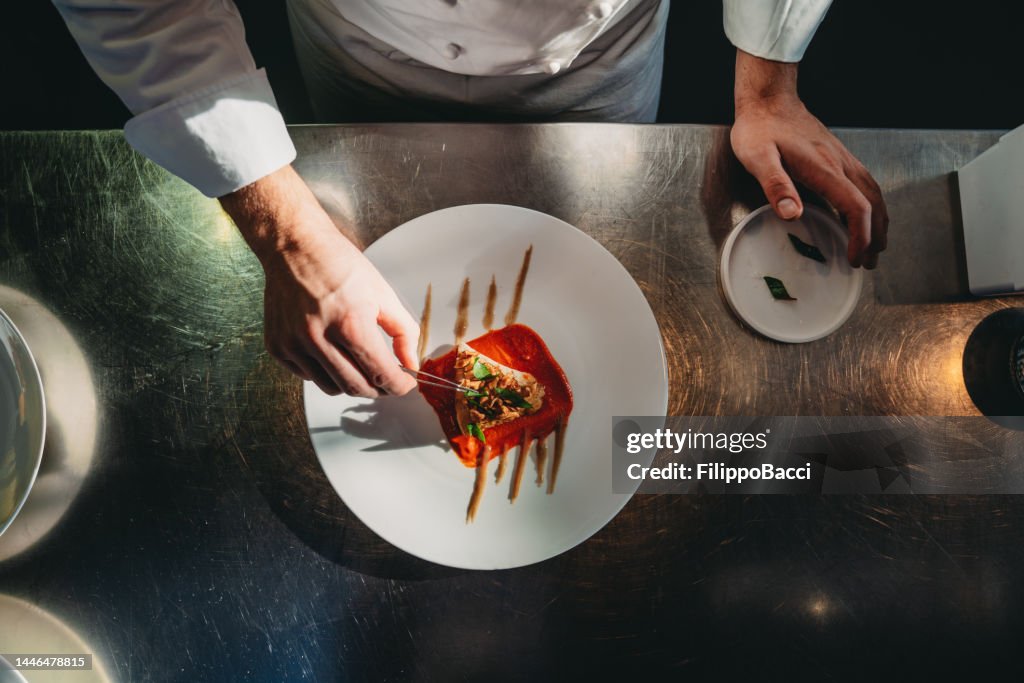 Ein Koch beendet die Zubereitung des Tellers