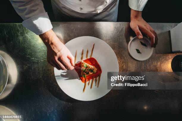 un chef está terminando la preparación del plato - plato vajilla fotografías e imágenes de stock