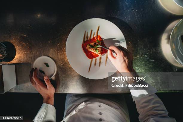 a chef is finishing the preparation of the plate - chef finishing stock pictures, royalty-free photos & images