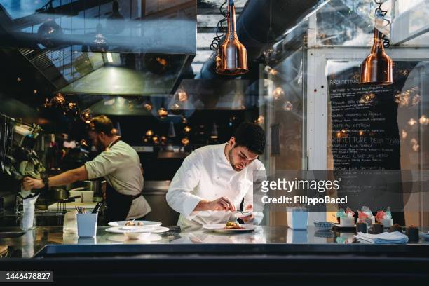 a chef is cooking in his restaurant's kitchen - kitchen cooking imagens e fotografias de stock