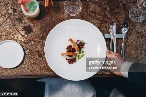 un cameriere sta servendo un piatto in un ristorante di fascia alta - gourmet foto e immagini stock