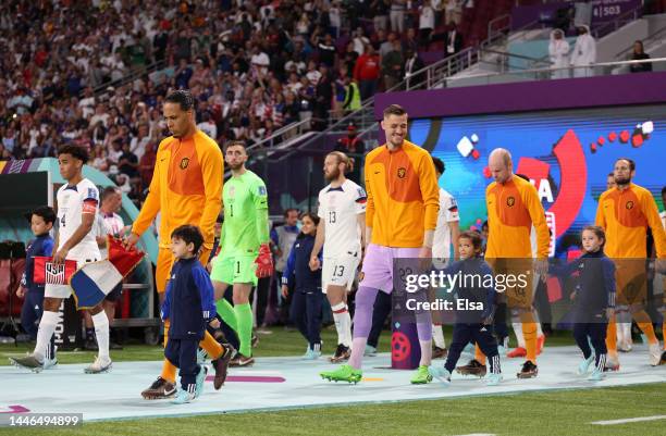 Netherlands players walk into the pitch with escort kids prior to the FIFA World Cup Qatar 2022 Round of 16 match between Netherlands and USA at...