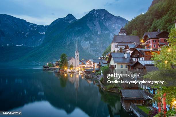 illuminated hallstatt village and hallstatter see lake in austria at dusk - austria foto e immagini stock