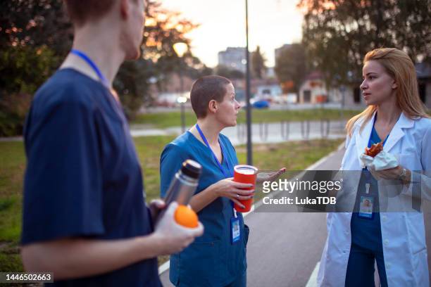 um homem e duas mulheres que trabalham em um bate-papo no hospital durante uma pausa para o café - hot nurse - fotografias e filmes do acervo