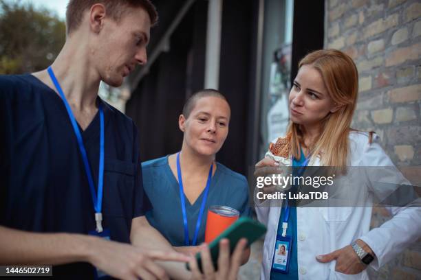 a male nurse is showing something to his colleagues on a mobile phone - coffee break outside stock pictures, royalty-free photos & images