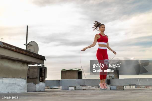 young woman exercising with skipping rope on rooftop - skipping along stock pictures, royalty-free photos & images