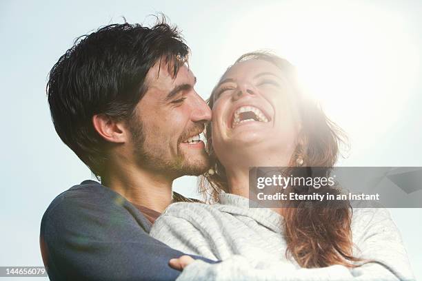 young couple laughing together, hugging outdoors - malay couple stock pictures, royalty-free photos & images