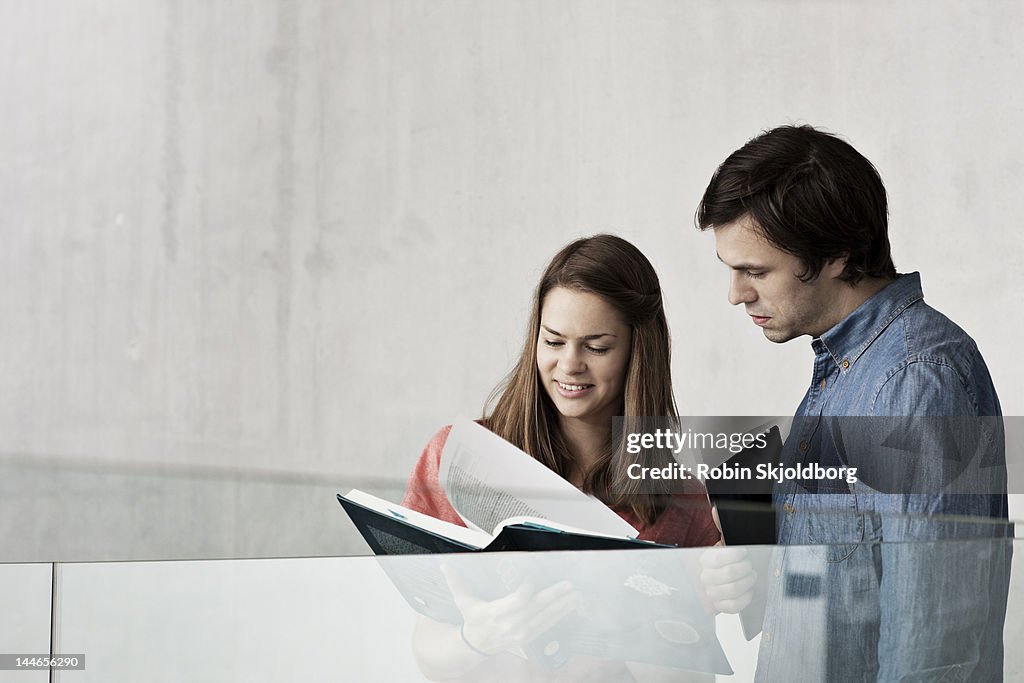 Woman and man looking in book, girl laughing.