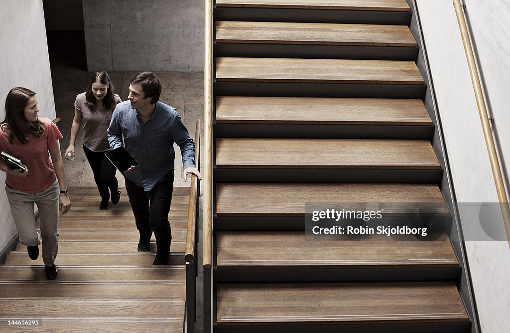 Two women and a man walking on stairs.