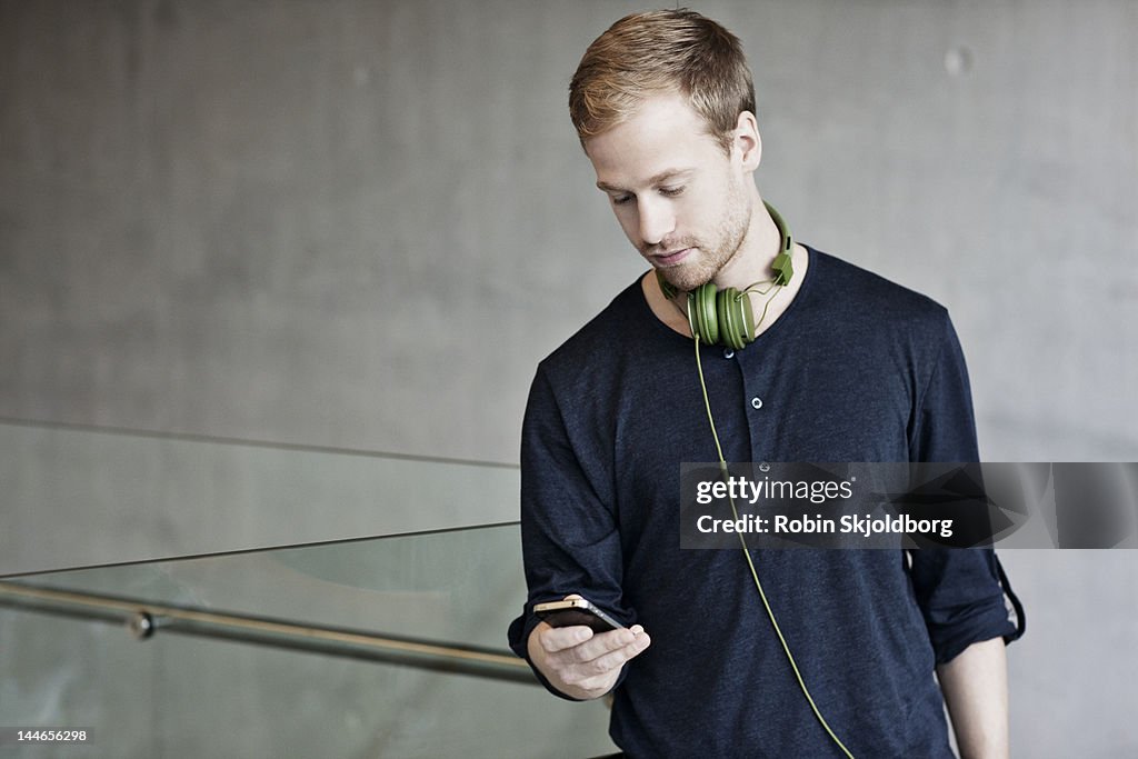 Man with headphones looking at mobile phone.