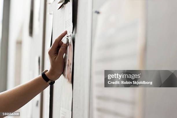 womans hand on noticeboard. - tablón de anuncios fotografías e imágenes de stock