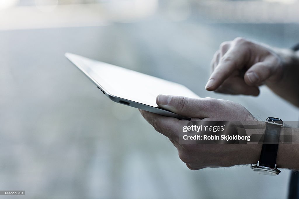 Closeup on mans hands holding tablet computer.
