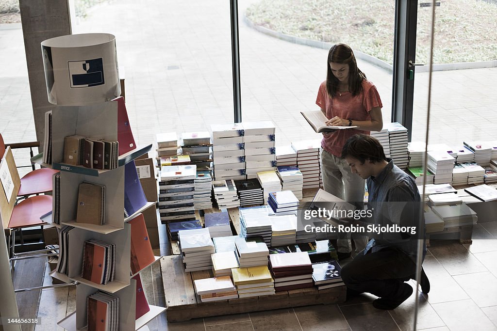 Man and women looking at books in bookshop.