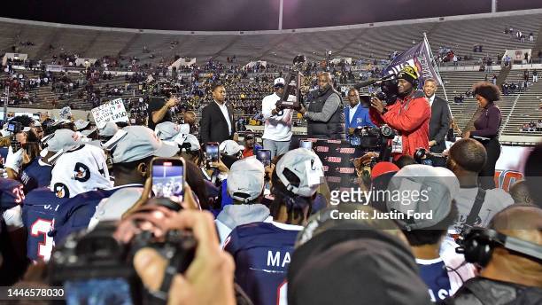 Head coach Deion Sanders of the Jackson State Tigers is handed the 2022 Cricket Wireless SWAC Football Championship Trophy after the game against the...