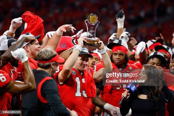 Stetson Bennett of the Georgia Bulldogs celebrates with the MVP trophy after defeating the LSU Tigers in the SEC Championship game at Mercedes-Benz...