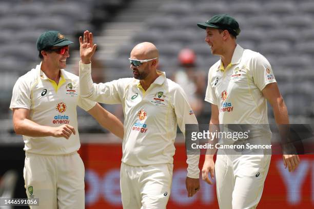 Nathan Lyon of Australia celebrates with Pat Cummins and Cameron Green of Australia after taking the wicket of Kraigg Braithwaite of the West Indies...