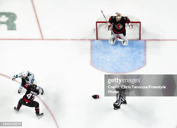 Anton Forsberg of the Ottawa Senators looks on as his teammate Mark Kastelic fights Jonah Gadjovich of the San Jose Sharks during the second period...