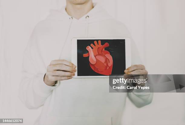 unrecognizable male holds digital table showing heart - blood flow photos et images de collection