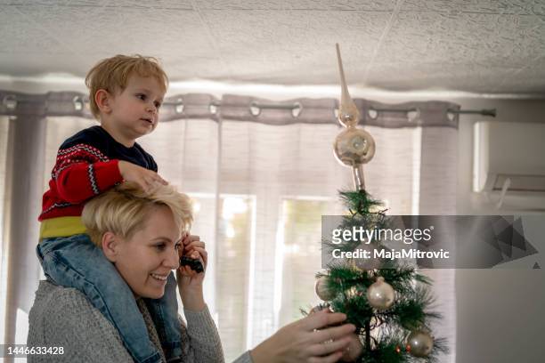 happy mother decorating the christmas tree with her son - baby winter farm son stock pictures, royalty-free photos & images