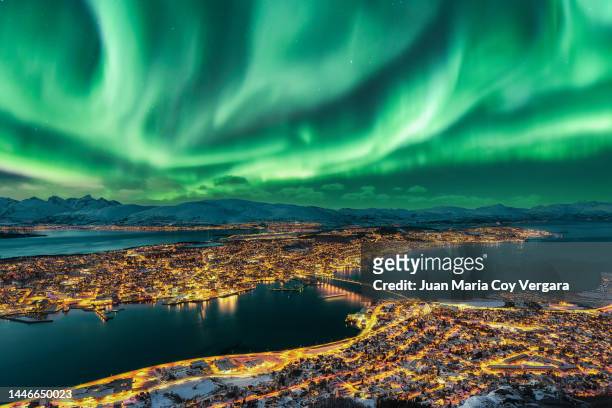 aurora borealis dancing over tromso urban skyline, northern norway - polarlicht stock-fotos und bilder
