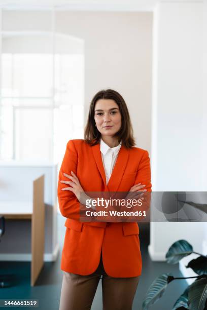 confident businesswoman with arms crossed in office - röd blazer bildbanksfoton och bilder