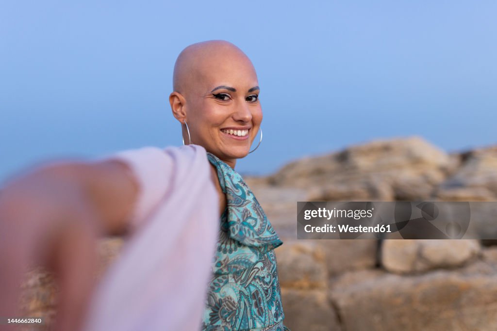 Happy woman with alopecia enjoying at sunset