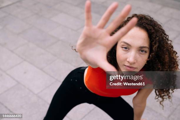 young woman showing stop gesture at footpath - hand geste halt stock-fotos und bilder