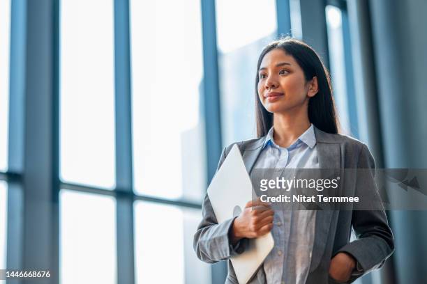 we are leading and inspiring as a woman equality. confident low-angle view of an asian businesswoman holding a laptop in the financial business office. - low confidence stock pictures, royalty-free photos & images