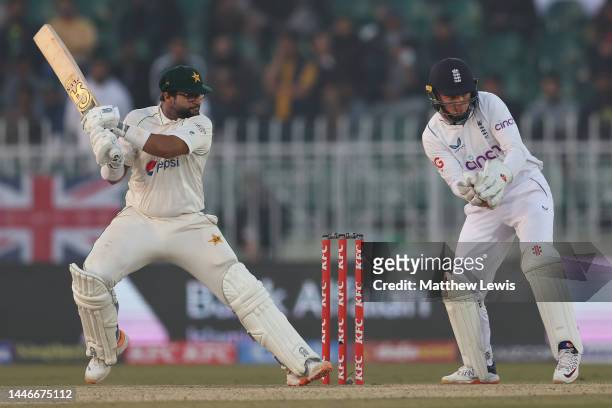 Imam-Ul-Haq of Pakistan hits the ball towards the boundary, as Ollie Pope of England watches on during the First Test Match between Pakistan and...