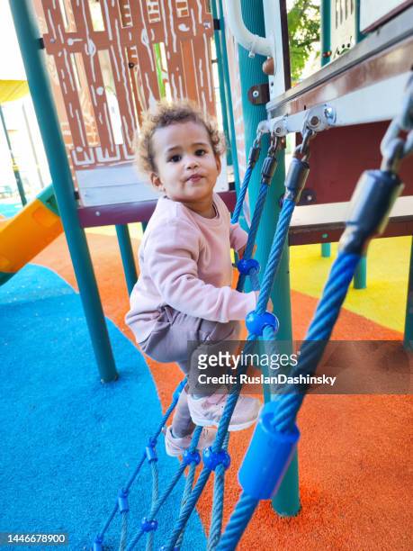 happy baby girl plays on the playground. outdoor urban park. - baby climbing stock pictures, royalty-free photos & images