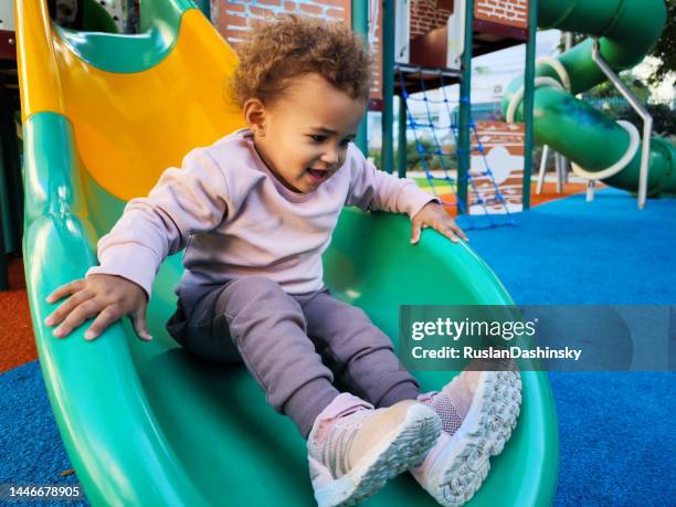 happy baby girl plays on the playground. outdoor urban park. - etiopiskt ursprung bildbanksfoton och bilder