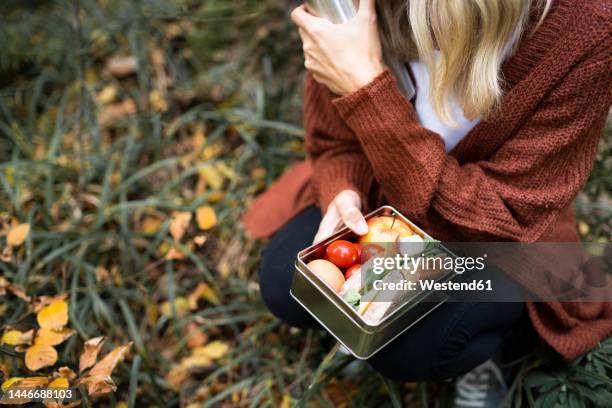 mature woman with lunch box crouching in autumn park - sack lunch stock pictures, royalty-free photos & images