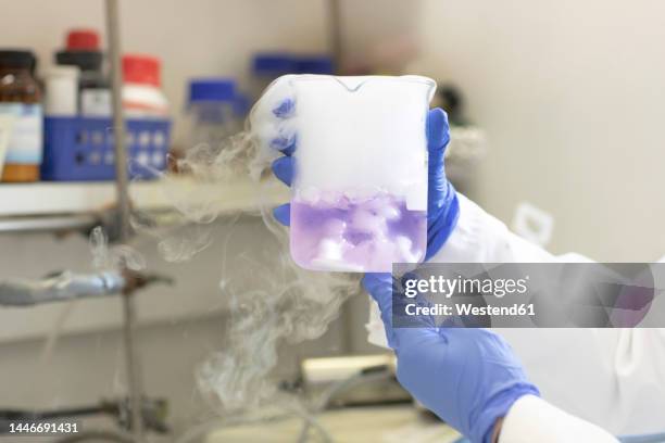 hands of scientist experimenting with liquid nitrogen in laboratory - liquid nitrogen foto e immagini stock