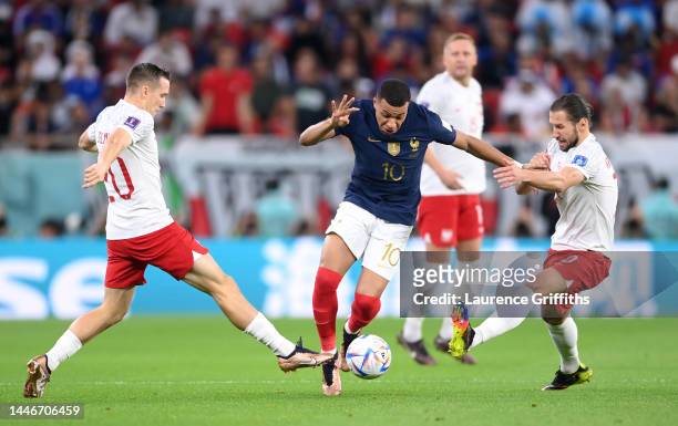 Kylian Mbappe of France battles for possession with Piotr Zielinski and Grzegorz Krychowiak of Poland during the FIFA World Cup Qatar 2022 Round of...