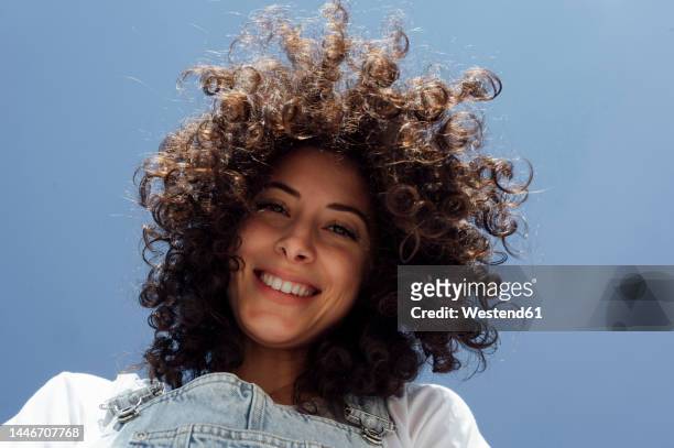 happy beautiful woman with curly hair under blue sky - one young woman only photos et images de collection