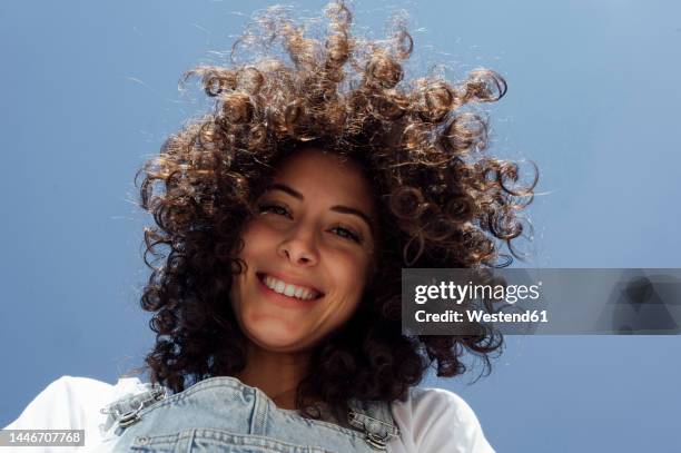 happy beautiful woman with curly hair under blue sky - one young woman only foto e immagini stock