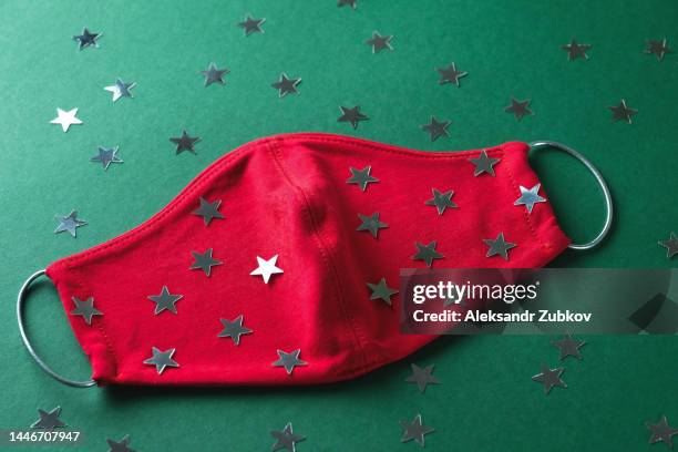 protective red medical face mask and colorful confetti on a green christmas background. prevention and prevention of the spread of the covid 19 pandemic. protection against viruses, infections, and pneumonia. the concept of a happy healthy christmas. - jan 19 stock pictures, royalty-free photos & images