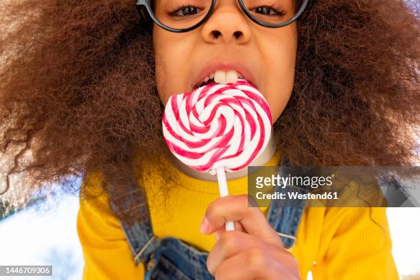 girl with buck teeth eating lollipop - buck teeth stock-fotos und bilder