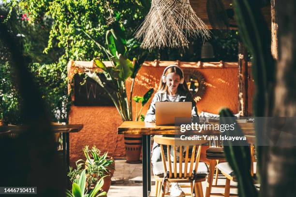 successful woman is working remotely in a bali style cafe - hot desking arbeitsplatz stock-fotos und bilder