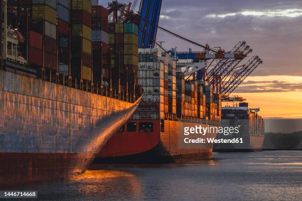 germany, hamburg, container ships in port of hamburg at dusk - container stock-fotos und bilder