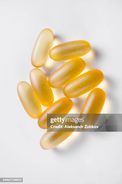 omega-3 fish oil capsules, isolated on a white background or a wooden table. healthy lifestyle, prevention and treatment of diseases. taking food supplements and vitamins. biologically active additive. intake of healthy fats. - fish oil stock photos et images de collection