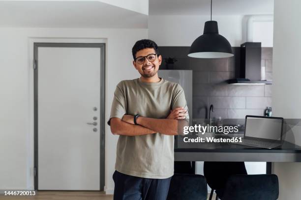 smiling young man with arms crossed at home - su 27 foto e immagini stock