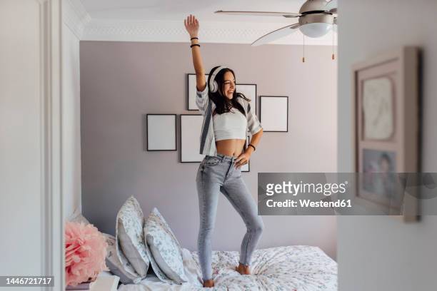 girl wearing headphones dancing on bed in bedroom - one girl only stock pictures, royalty-free photos & images