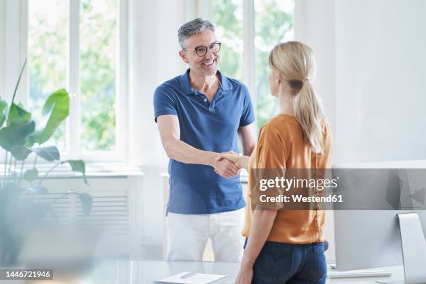 happy mature doctor shaking hands with patient at medical practice - polo shirt imagens e fotografias de stock