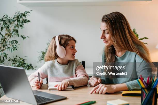 mother helping girl in study sitting with laptop on table at home - 7 stock-fotos und bilder