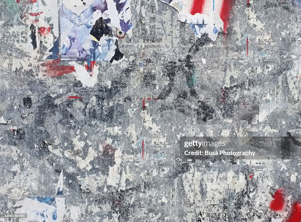Scratched layers of posters and placards on a street wall
