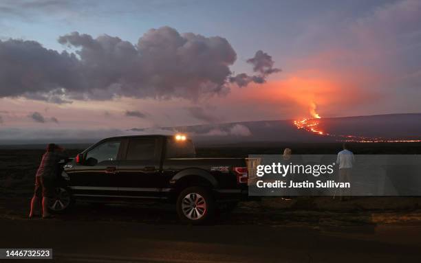 People stand on the side of the road to photograph the eruption of the Mauna Loa volcano on December 04, 2022 near Hilo, Hawaii. For the first time...