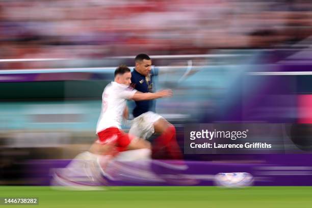 Kylian Mbappe of France battles for possession with Matty Cash of Poland during the FIFA World Cup Qatar 2022 Round of 16 match between France and...