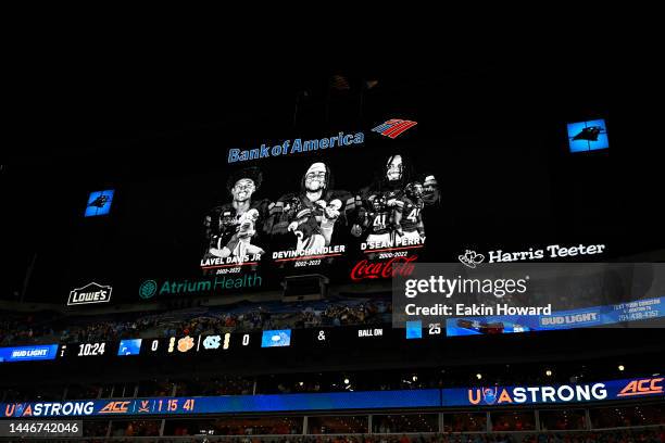 Players Lavel Davis Jr., Devin Chandler, and D'Sean Perry are seen on the video board during a moment of silence before the ACC Championship game...